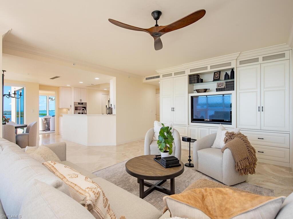 Image 3: Living area with ceiling fan, a chandelier, and light marble finish floors