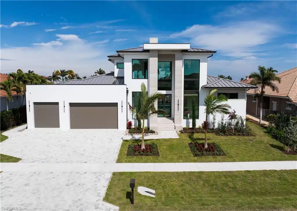 Image 1: Modern home with a standing seam roof, a garage, decorative driveway, and a front yard