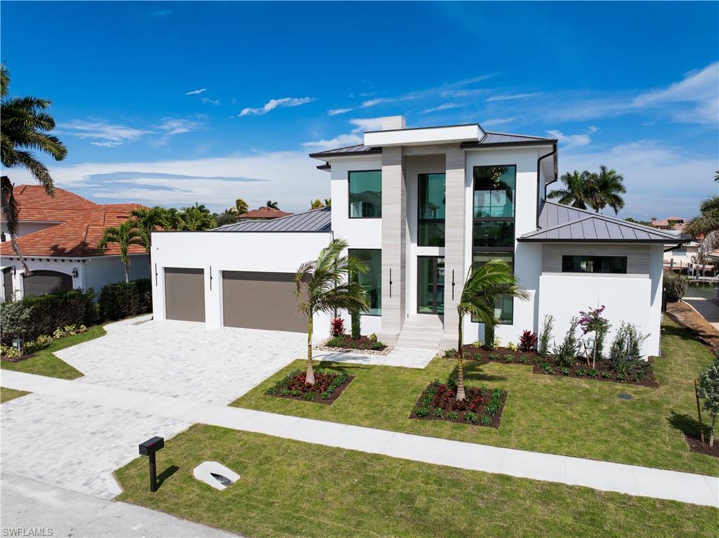 Image 2: Contemporary home featuring a standing seam roof, a garage, decorative driveway, a front yard, and stucco siding