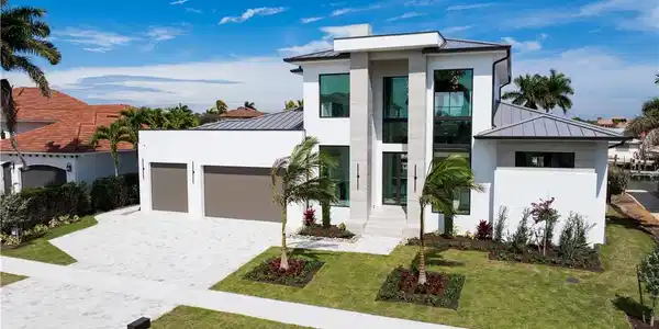 Image 2: Contemporary home featuring a standing seam roof, a garage, decorative driveway, a front yard, and stucco siding