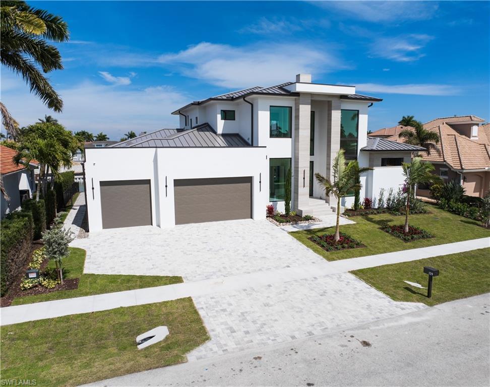 Image 3: Contemporary home featuring a standing seam roof, a garage, a front yard, decorative driveway, and stucco siding