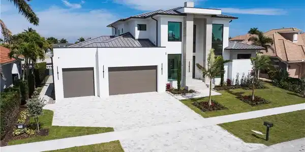 Image 3: Contemporary home featuring a standing seam roof, a garage, a front yard, decorative driveway, and stucco siding