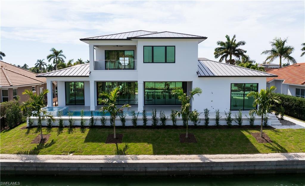 Image 4: Modern home with a standing seam roof, a garage, decorative driveway, and a front yard