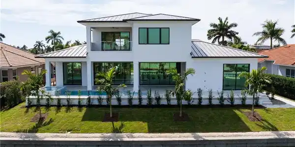 Image 4: Modern home with a standing seam roof, a garage, decorative driveway, and a front yard