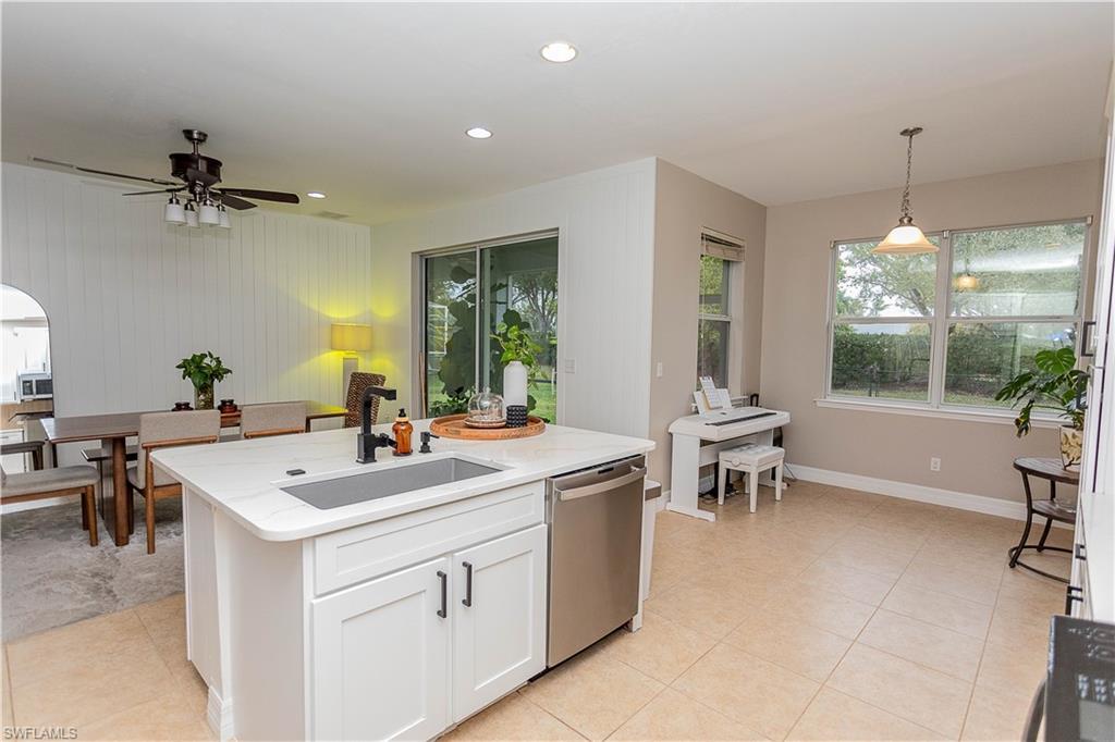 Image 3: Kitchen featuring pendant lighting, stainless steel appliances, white cabinetry, light stone counters, and a kitchen island with sink
