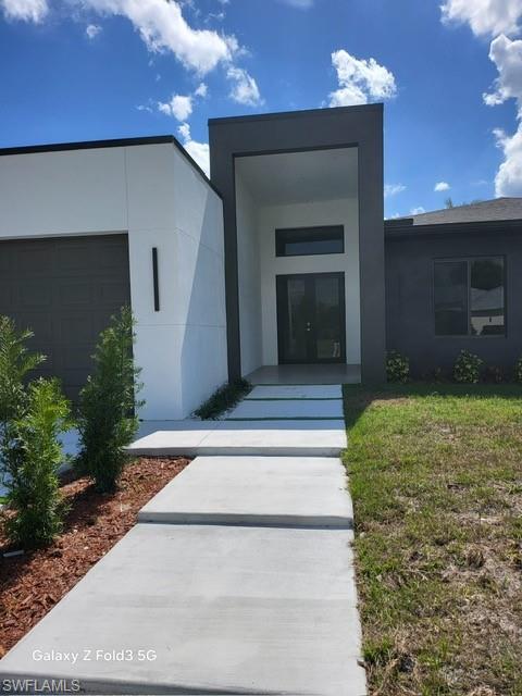 Image 1: Entrance to property featuring stucco siding and a garage