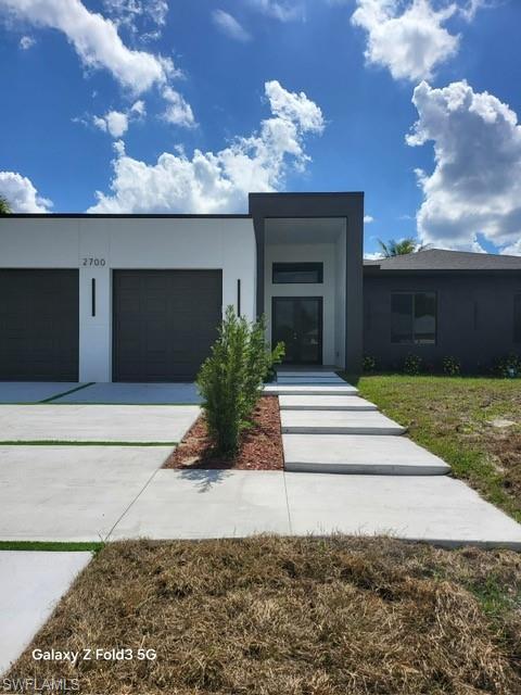 Image 2: Contemporary home with stucco siding, a garage, and concrete driveway