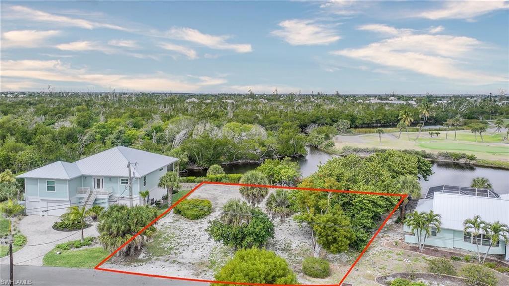 Image 2: Aerial view of property and surrounding area featuring property parcel outlined and a nearby body of water