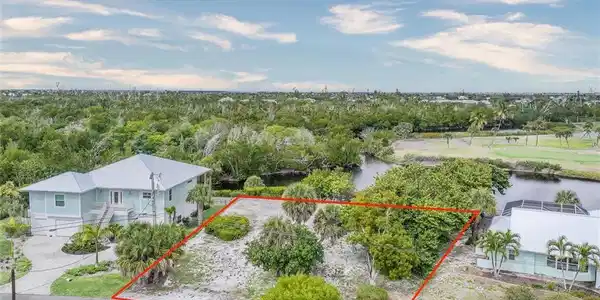 Image 2: Aerial view of property and surrounding area featuring property parcel outlined and a nearby body of water
