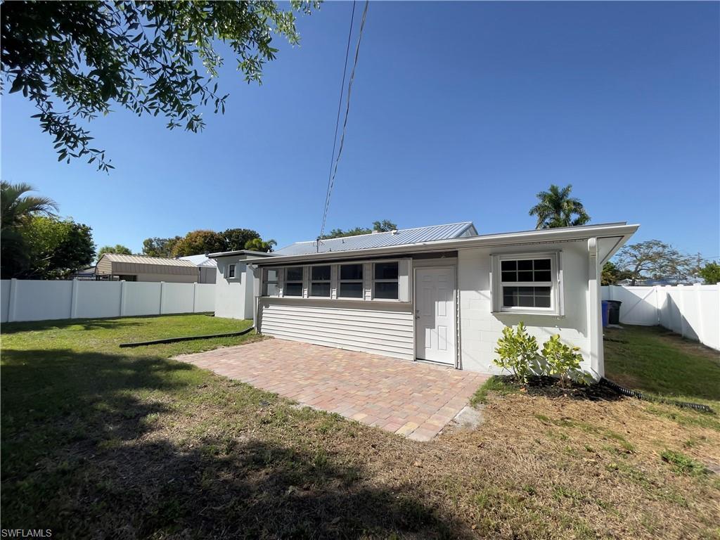 Image 3: Back of property with a patio area, a fenced backyard, concrete block siding, and a metal roof