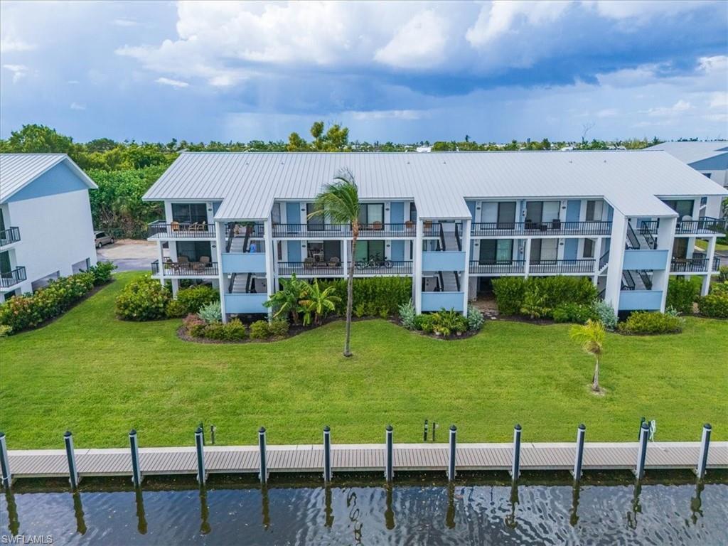 Image 4: Rear view of house with a water view, a balcony, and a lawn