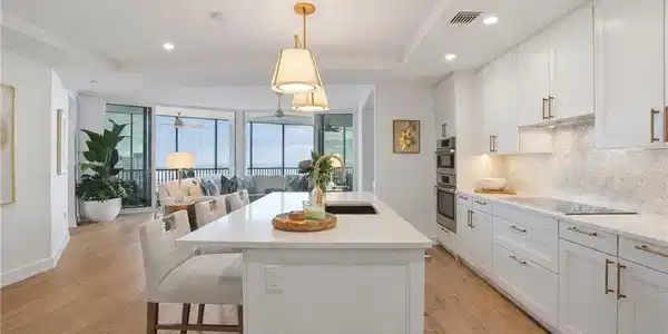 Image 2: Kitchen featuring white cabinetry, open floor plan, pendant lighting, a center island with sink, and a breakfast bar area - Virtually Edited Image