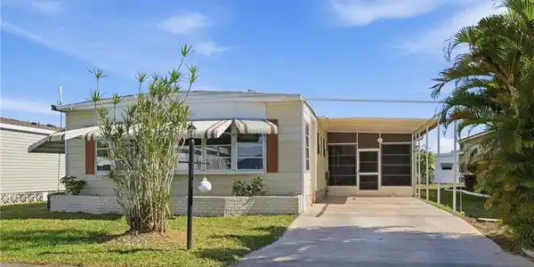 Image 2: Manufactured / mobile home with a front yard, concrete driveway, a sunroom, and a carport