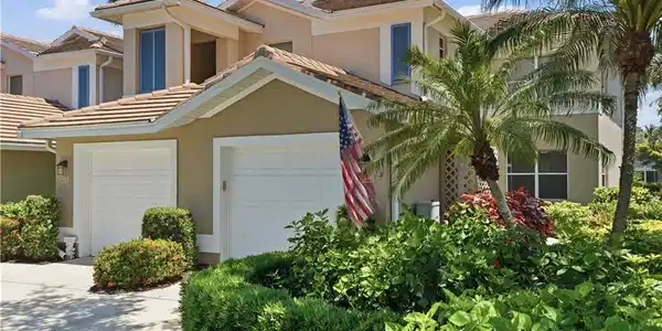 Image 2: Stucco exterior featuring dual garage doors, a tile roof, and dormer windows
