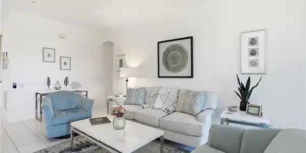 Image 4: Spacious living area featuring white tile flooring, neutral wall tones, and a recessed archway