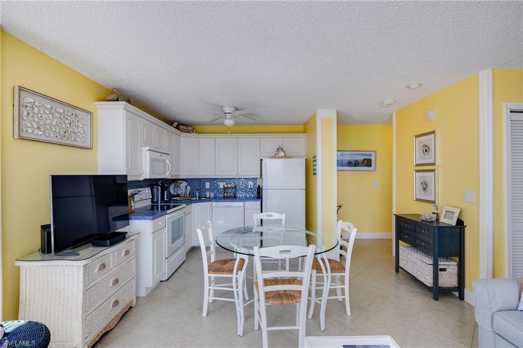 Image 3: Kitchen featuring white appliances, white cabinetry, dark countertops, backsplash, and a textured ceiling