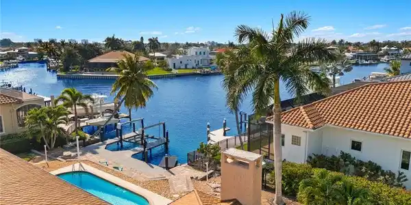 Image 2: Dock area featuring boat lift, an outdoor pool, a water view, a residential view, and a patio