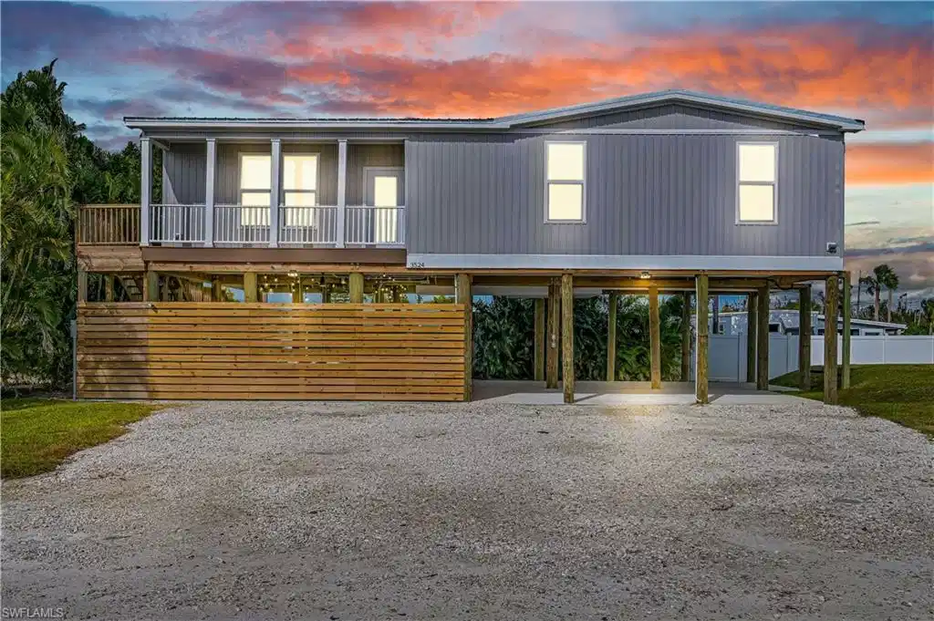 Image 1: Raised beach house featuring driveway and a carport