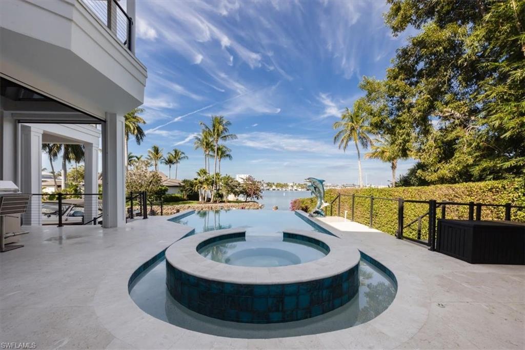 Image 3: View of swimming pool featuring a patio area, a pool with connected hot tub, and a water view