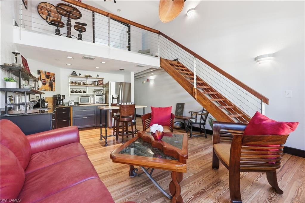 Image 2: Living area with light wood-type flooring, a towering ceiling, and stairway