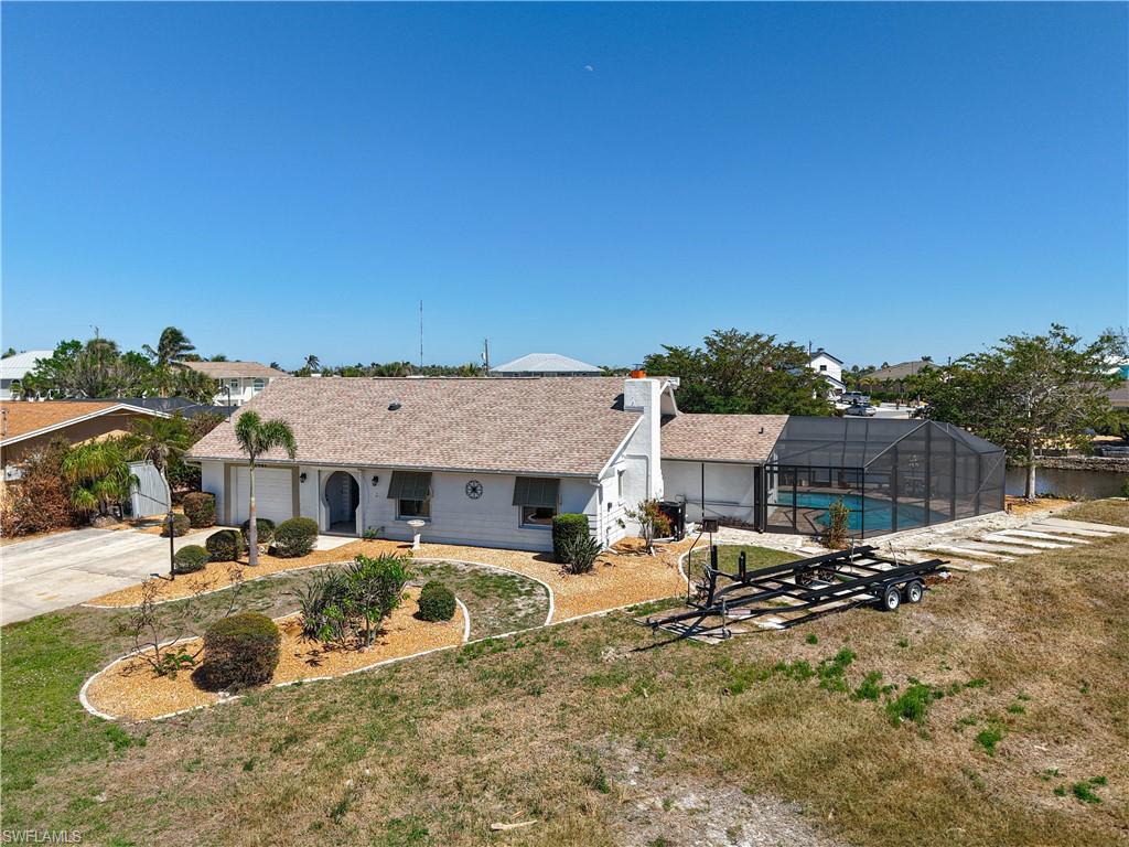 Image 2: View of front of house featuring glass enclosure, a front lawn, concrete driveway, and an outdoor pool