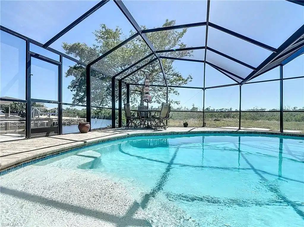 Image 1: Outdoor pool with a sunroom, glass enclosure, and a patio area