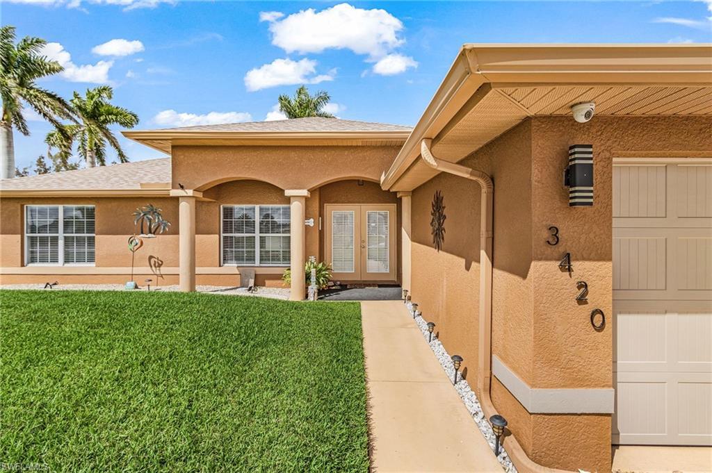 Image 4: View of exterior entry featuring french doors, a lawn, stucco siding, a porch, and a shingled roof