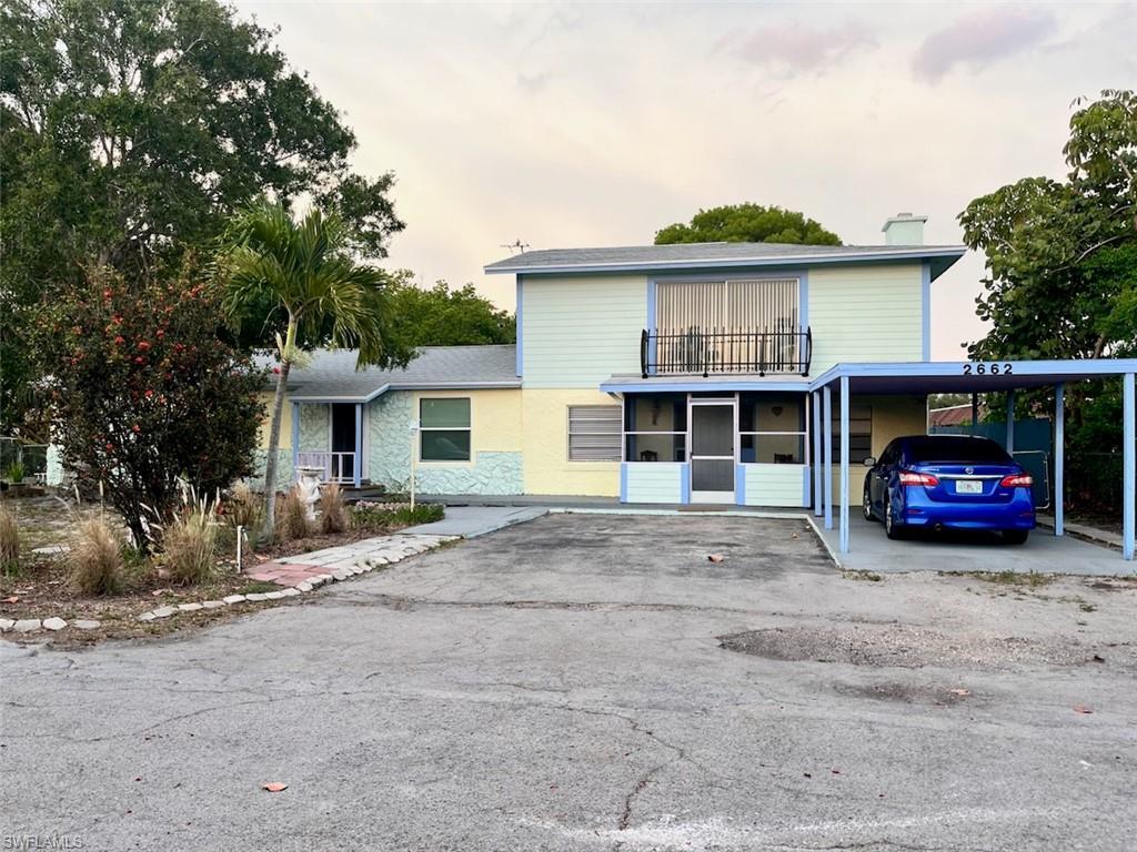 Image 2: View of front of house with a balcony, an attached carport, asphalt driveway, and a chimney