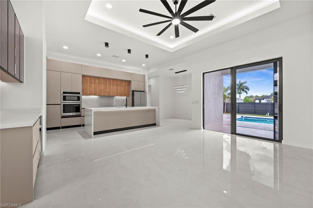 Image 4: Spacious open-concept kitchen featuring a large central island, integrated stainless steel appliances, and sleek flat-panel cabinetry