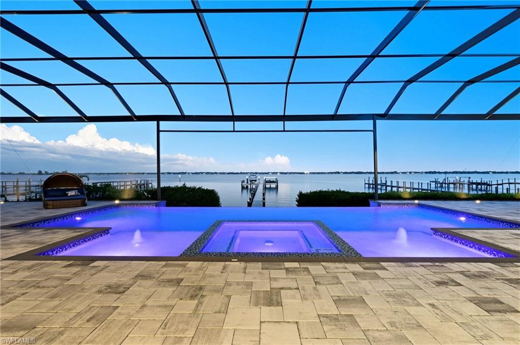 Image 3: View of swimming pool with glass enclosure, a water view, and a pool with connected hot tub