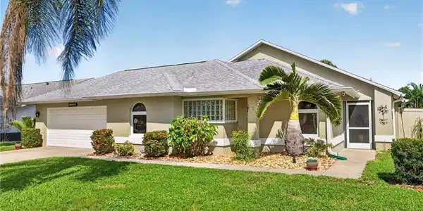 Image 2: Stucco exterior with an attached garage, a screened entry, and a pitched shingle roof