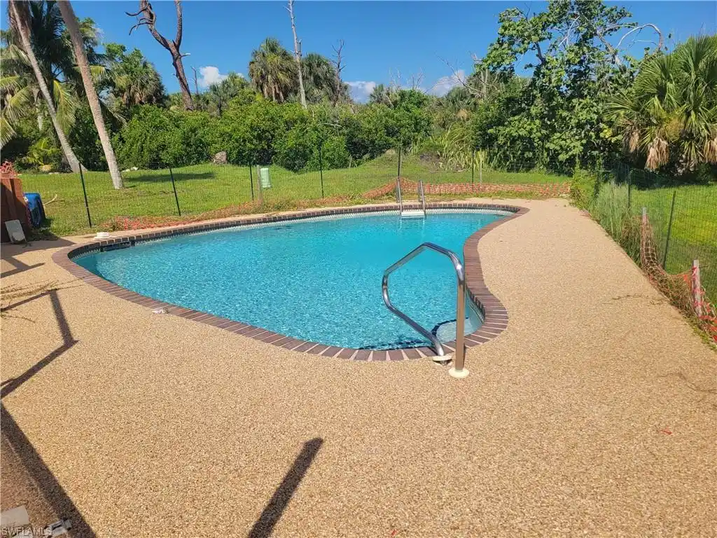 Image 1: Outdoor pool with a yard, view of scattered trees, and a patio area