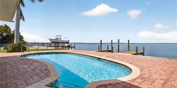 Image 2: Freeform swimming pool with integrated steps, surrounded by brick paver decking