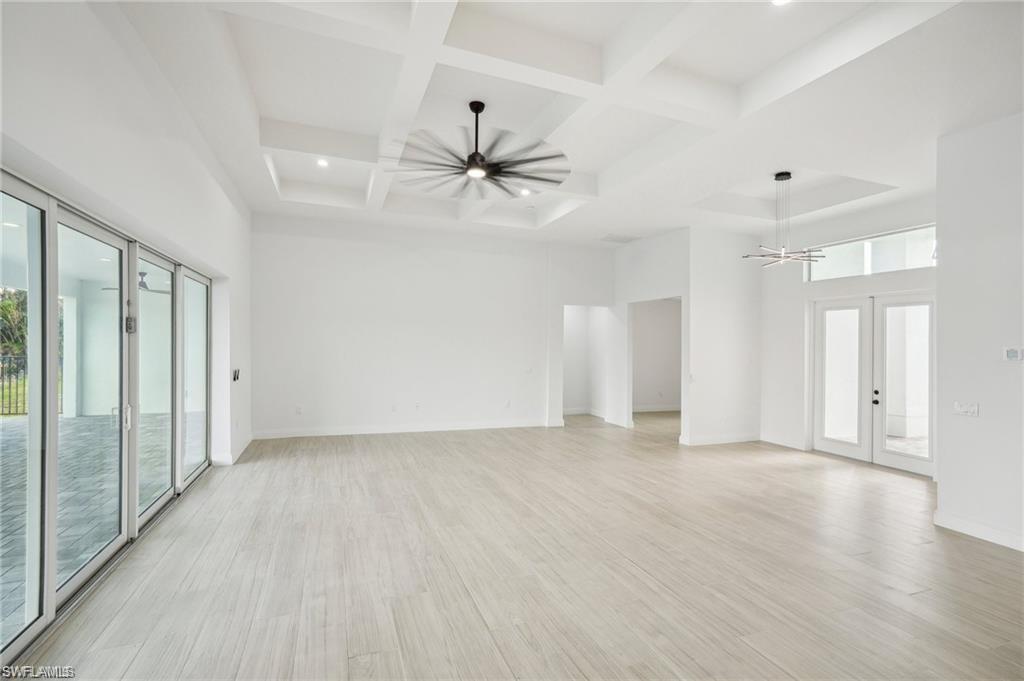 Image 4: Spare room with french doors, a towering ceiling, ceiling fan, and light hardwood / wood-style flooring