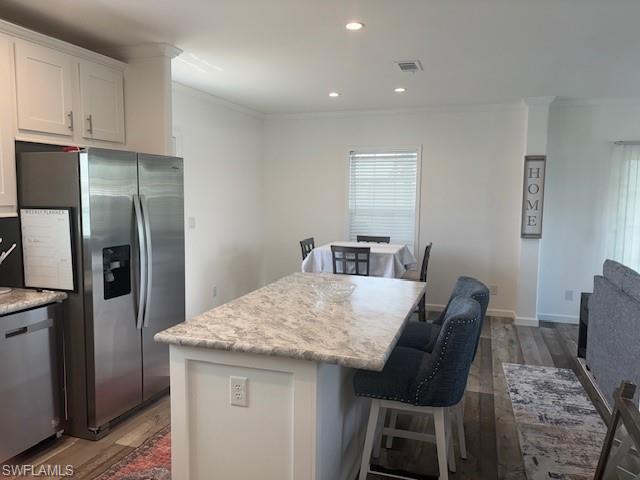 Image 4: Kitchen with a kitchen bar, appliances with stainless steel finishes, recessed lighting, dark wood finished floors, and white cabinets
