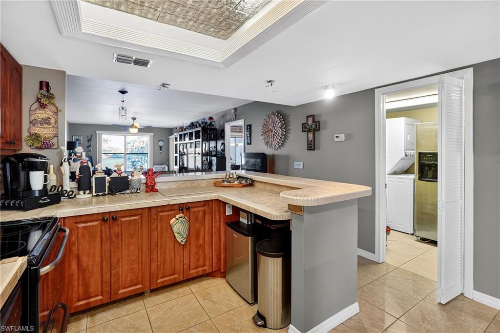 Image 4: Kitchen featuring an ornate ceiling, a peninsula, black electric range oven, light tile patterned floors, and a raised ceiling