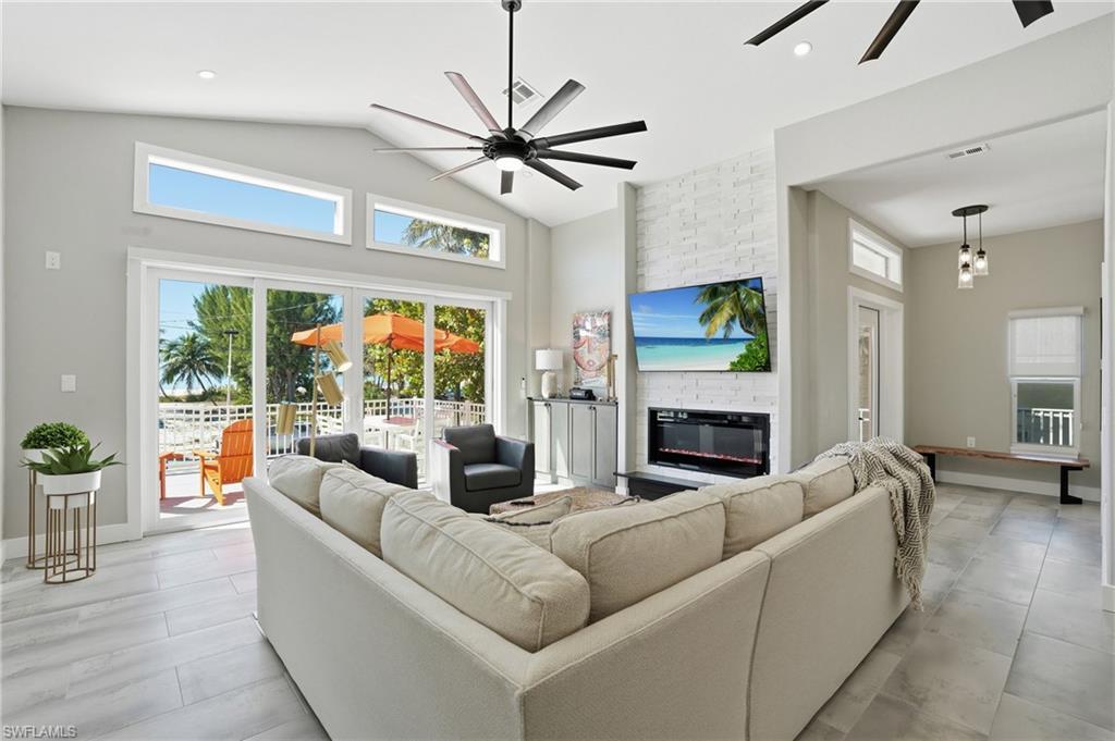 Image 3: Living area with a ceiling fan, a large fireplace, vaulted ceiling, and recessed lighting - Virtually Edited Image