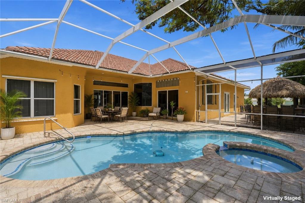 Image 3: Screened outdoor living area featuring a freeform pool, integrated spa, and pavers