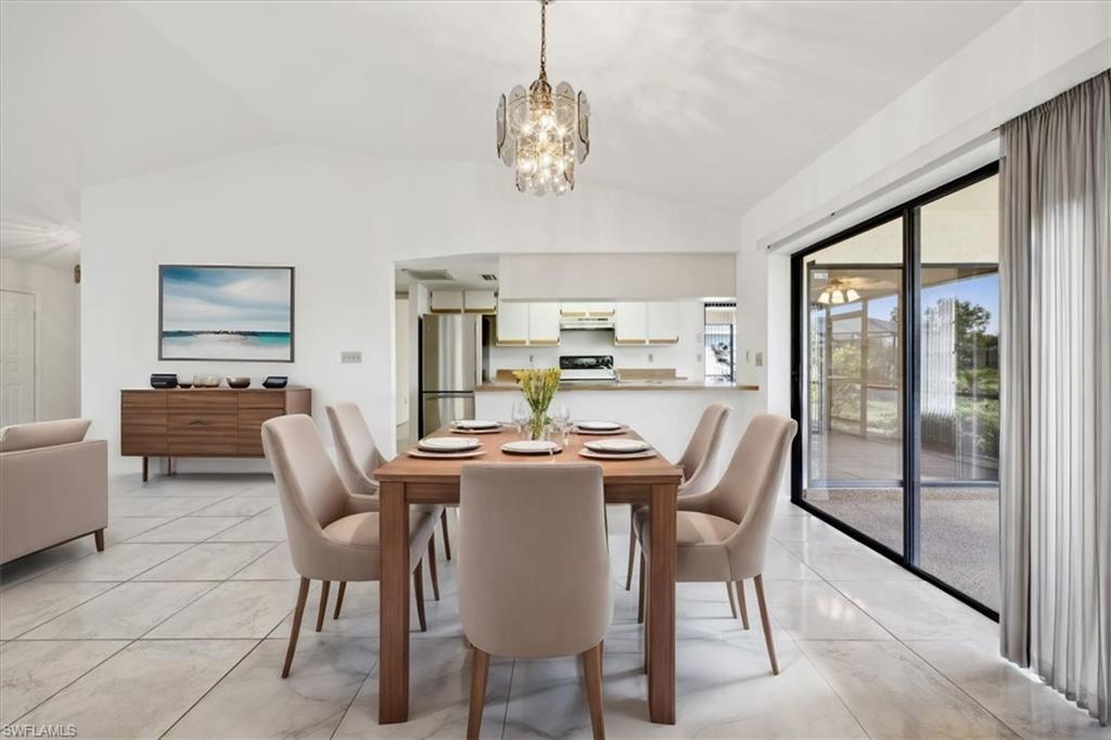 Image 1: Dining area with lofted ceiling and a chandelier