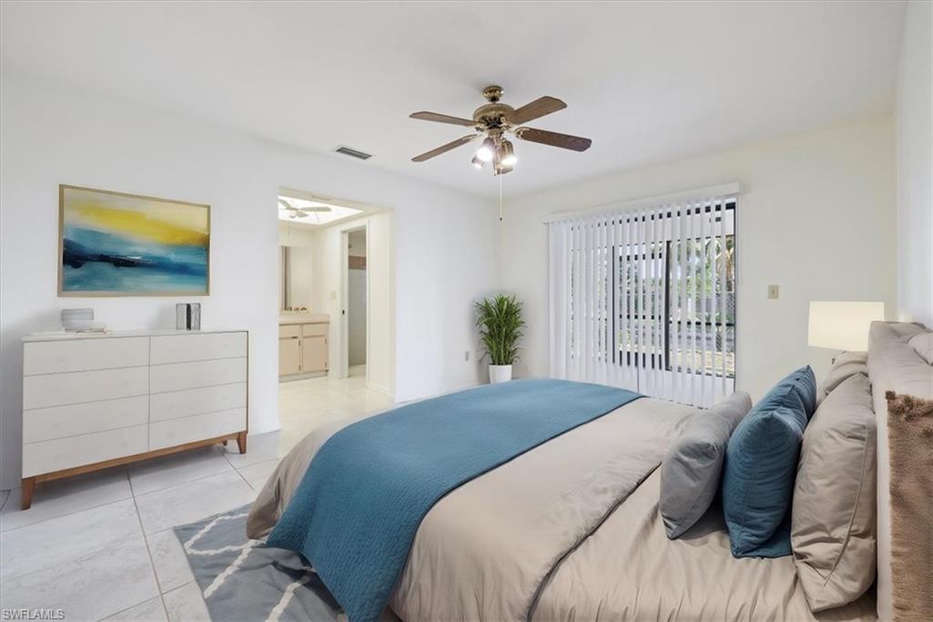 Image 4: Bedroom with light tile patterned floors, ceiling fan, and ensuite bath