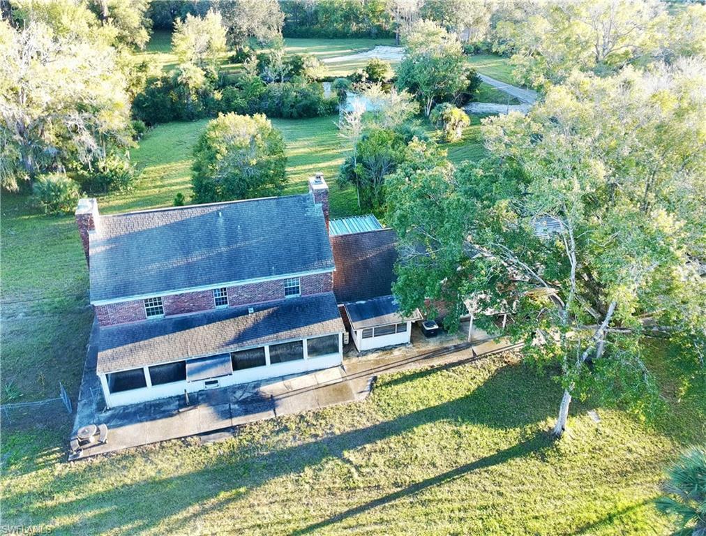Image 3: Aerial view of subject property featuring long porch and tree filled landscape