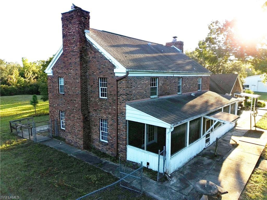 Image 4: East side of property with a chimney, brick siding, a porch, and a shingled roof