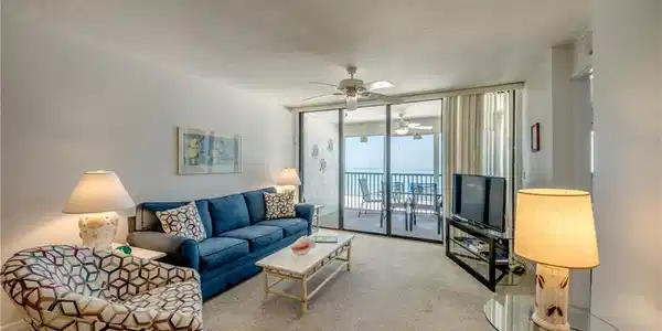 Image 3: Living area featuring direct patio access, ocean scenery, ceiling fan, and carpet flooring