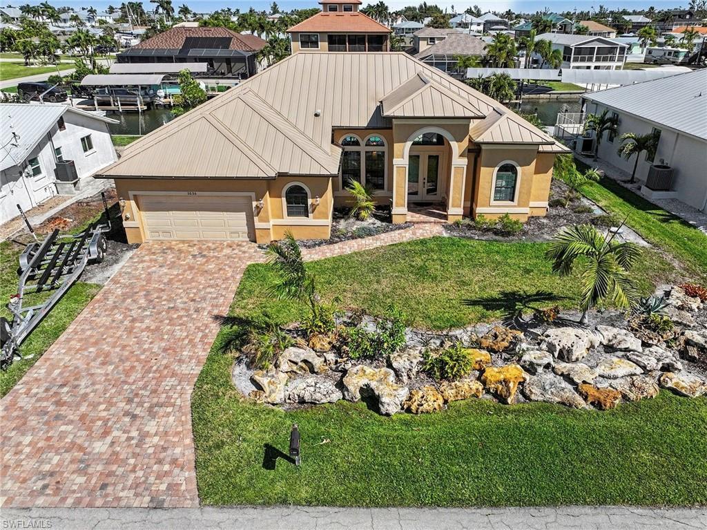 Image 1: View of front of house with stucco siding, decorative driveway, an attached garage, and french doors.  Has ample room for trailer storage to the side of the driveway.
