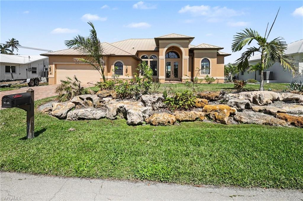 Image 2: Beautifully landscaped home with a standing seam roof, stucco siding, and attached 2 car garage.