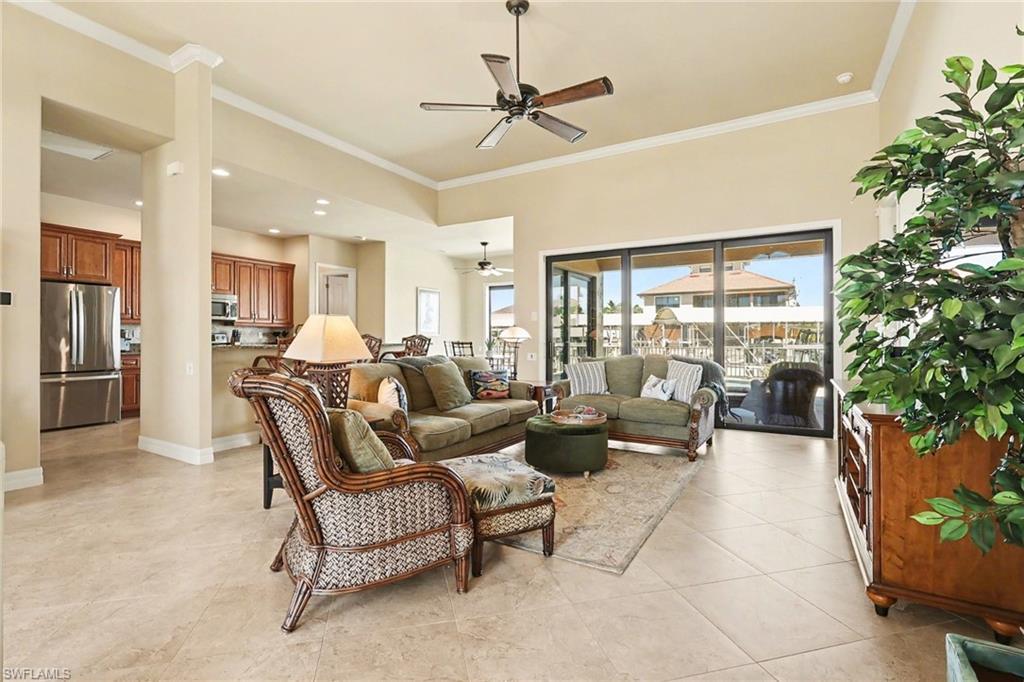 Image 4: Living room with ceiling fan, crown molding, and luxury tile patterned flooring.