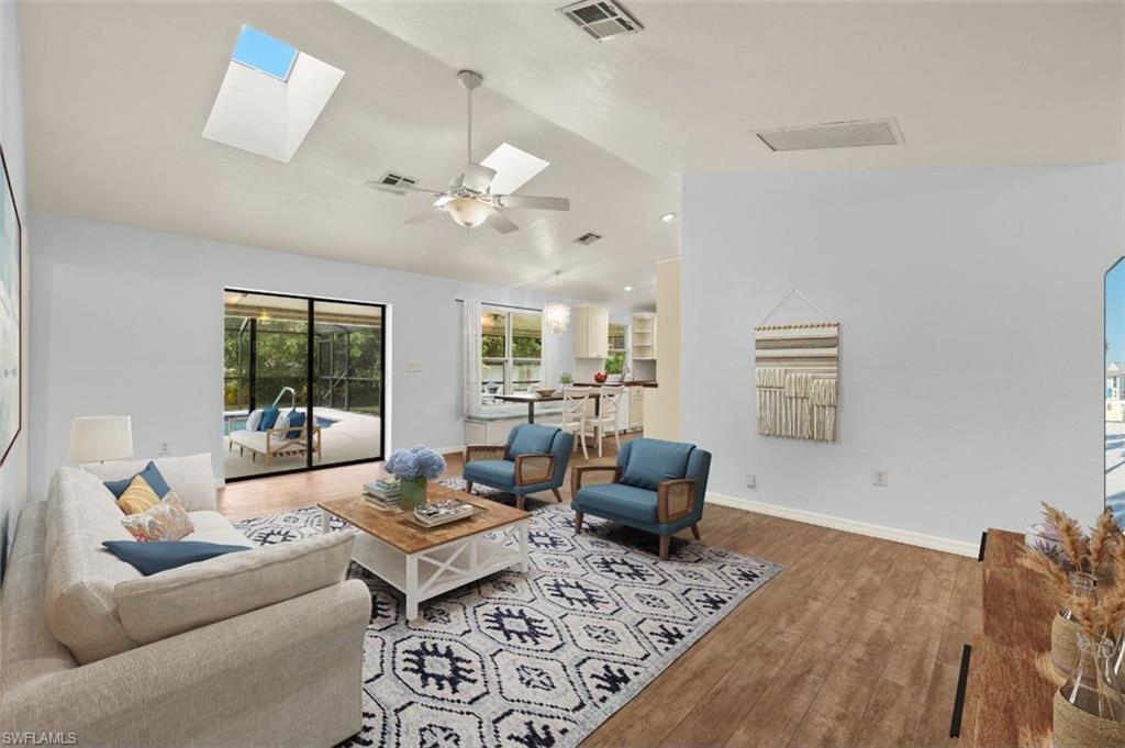 Image 2: Living room featuring lofted ceiling with skylight, wood-type flooring, and ceiling fan