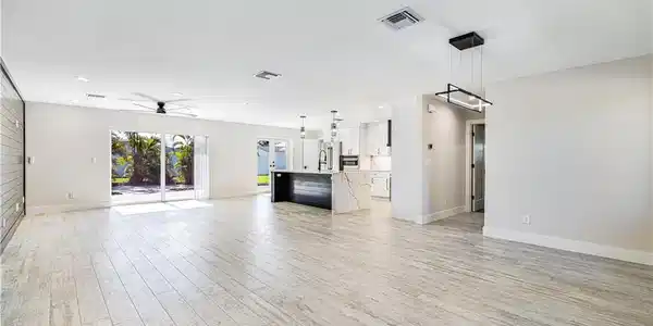 Image 4: Open-concept living area featuring wood-finish plank flooring, recessed ceiling lighting, and a modern chandelier