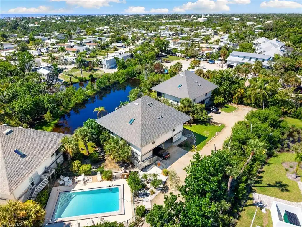 Image 1: Aerial view of residential area featuring a pool area and a large body of water
