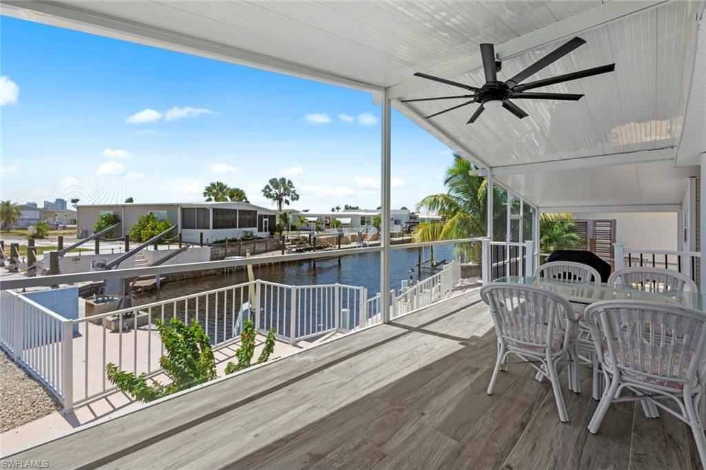 Image 1: Wooden deck featuring outdoor dining area, a water view, ceiling fan, and a residential view